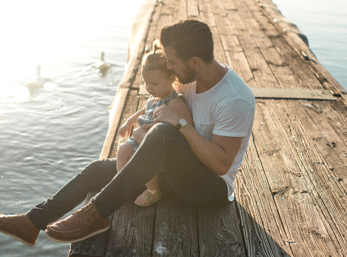 father sitting with child on a pier