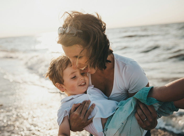 woman holding child on the beach